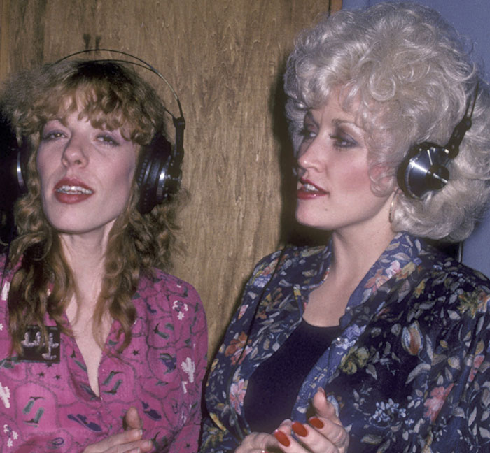 Dolly Parton's sister and Dolly wearing headphones during a recording session amid health struggles concerns.