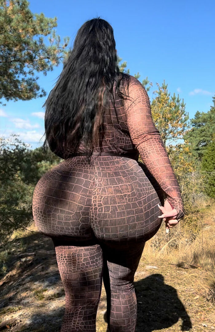 Woman outdoors showcasing results of multiple plastic surgery procedures including Brazilian Butt Lifts with textured outfit and long hair.