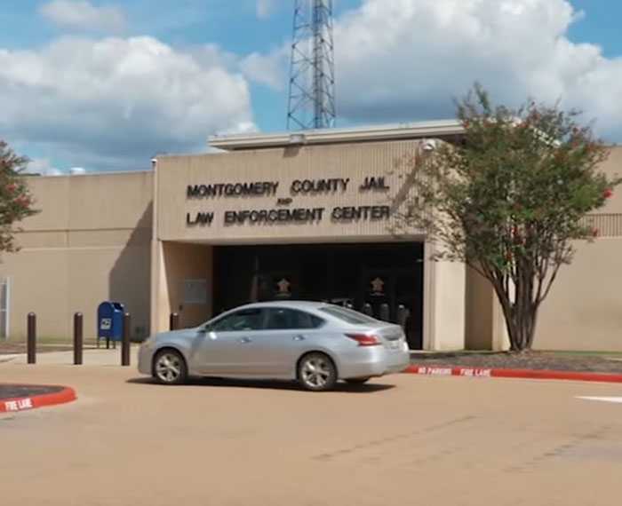 Montgomery County Jail and Law Enforcement Center building exterior with a car driving by under a blue sky.