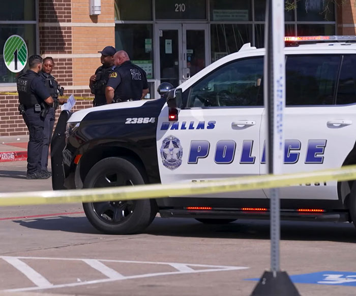 Dallas police officers standing outside a pet store with crime scene tape after a woman loses life following an argument.