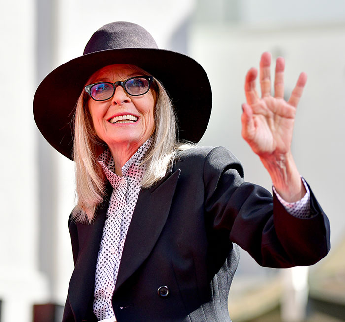 Diane Keaton wearing a black hat and glasses, smiling and waving, capturing a chilling detail to hear about her last moments.