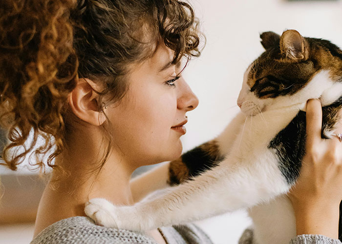 Woman holding a cat close, showcasing one of the bizarre cat hacks owners discovered that actually work for better pet care.