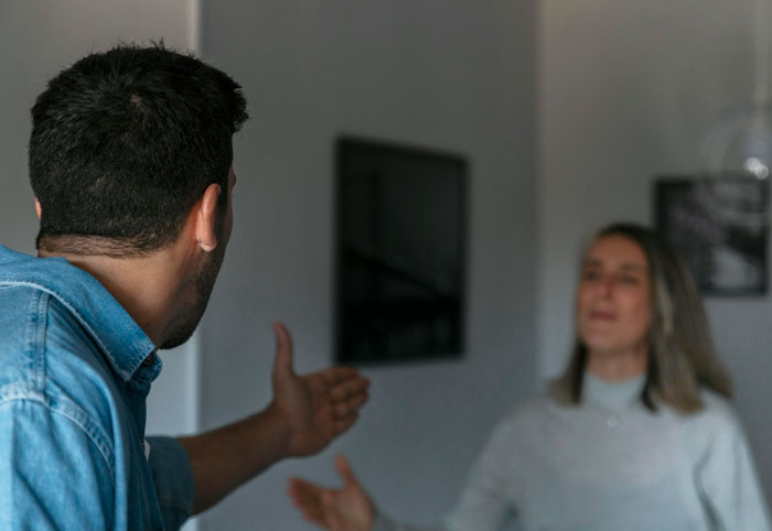 A man angrily confronting a woman indoors, illustrating interaction with a horrifyingly cruel person they’ve met.