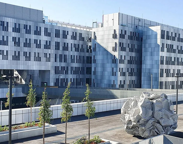 Modern hospital building exterior with sculpture, related to brain surgeon arrest and skull drilling incident.