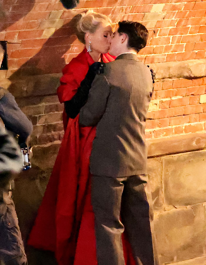 Gwyneth Paltrow and Timoth&eacute;e Chalamet sharing a tender moment against a brick wall at night.
