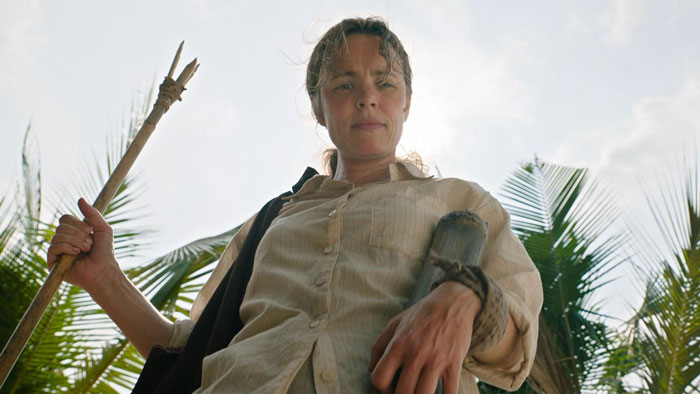 Rachel McAdams with a natural look holding a spear outdoors, surrounded by palm trees in a new film scene. Rachel McAdams with a natural look holding a spear outdoors, surrounded by palm trees in a new film scene.