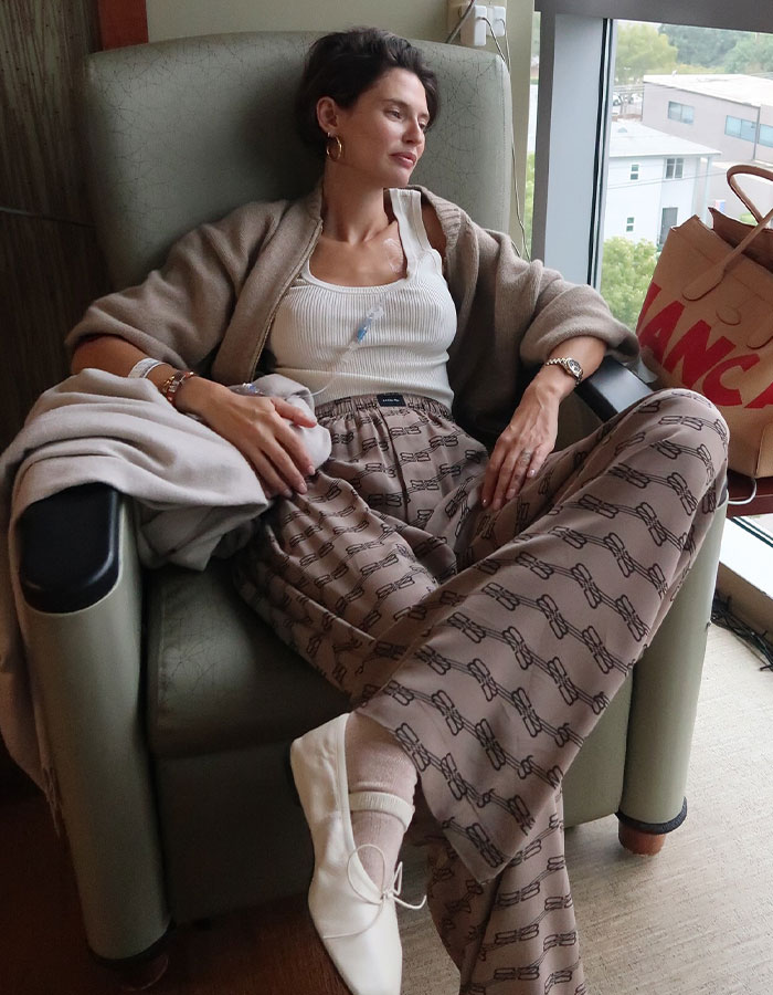 Ex-Victoria&rsquo;s Secret model sitting in a chair at home, appearing contemplative during her cancer battle.