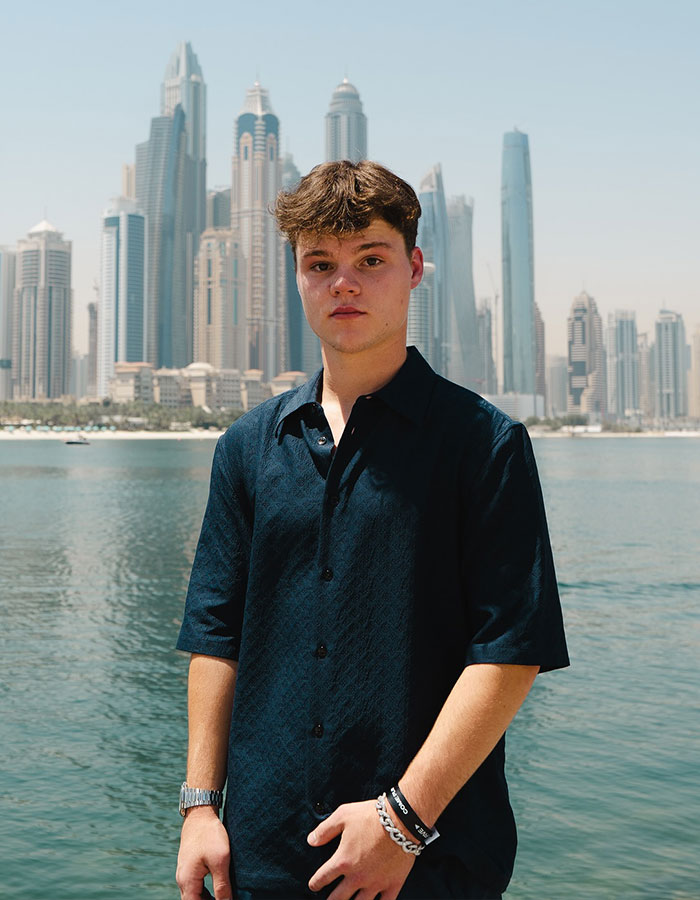 Young man in dark shirt standing near waterfront with skyscrapers, related to adult star and YouTube prankster news.