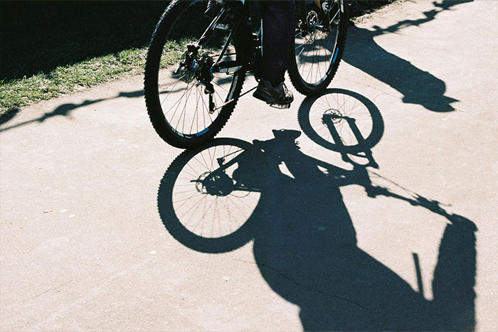 Shadow of a person riding a bicycle on pavement, illustrating a woman knocked unconscious by bird insurance claim denied.