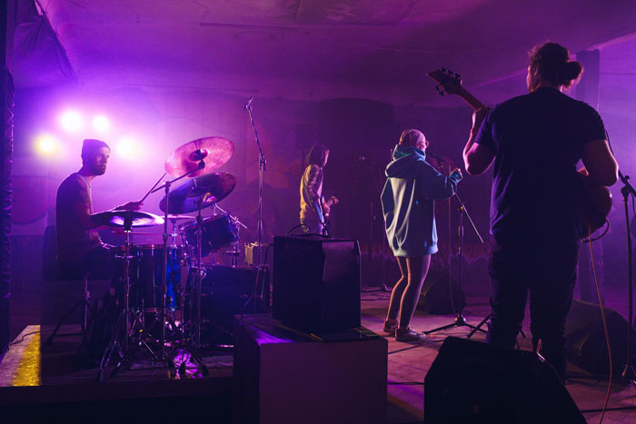 Band performing live on stage with vibrant purple lighting, highlighting the worst employees bosses have dealt with.
