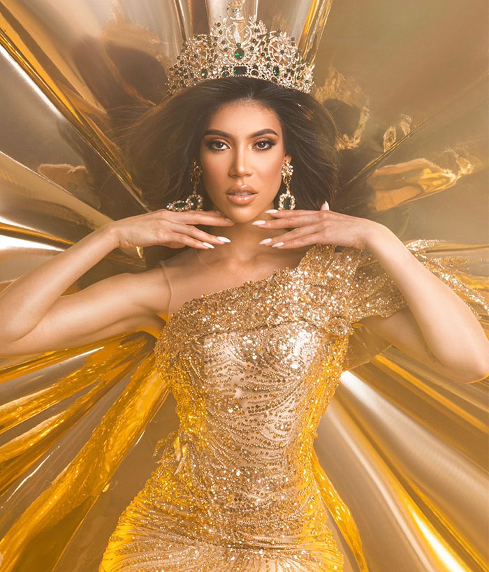 Miss Panama in a sparkling gold gown and crown, posing gracefully during an onstage moment in a beauty pageant.