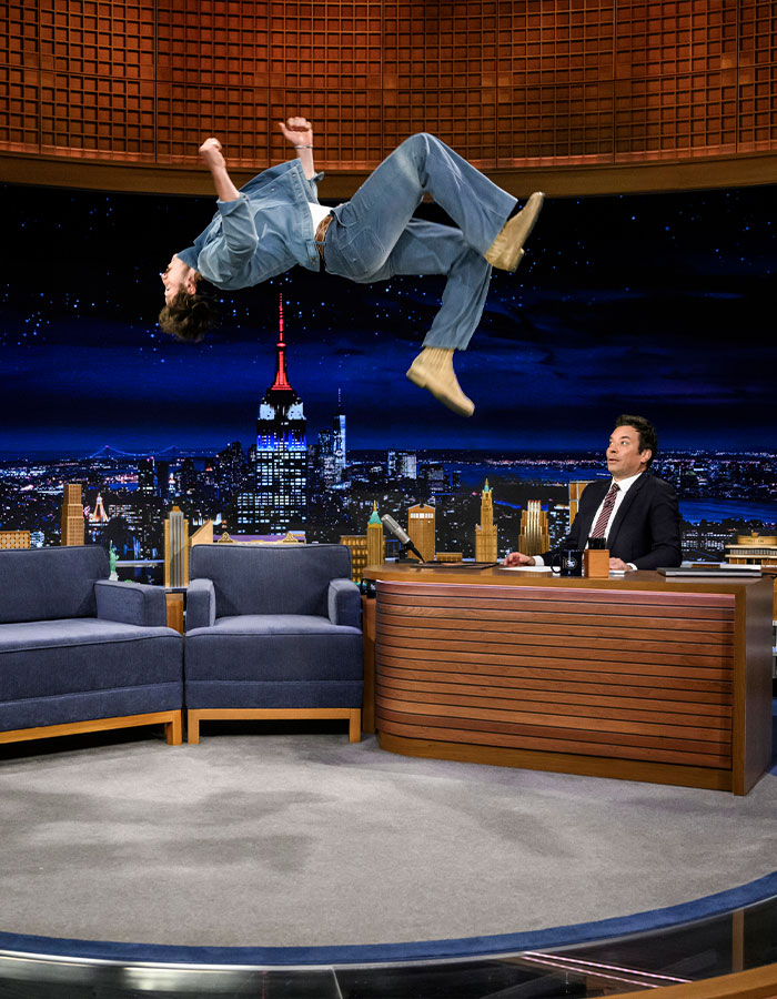 Man performing a backflip on a late-night talk show set, illustrating the viral Mormon Backflip Theory trend.