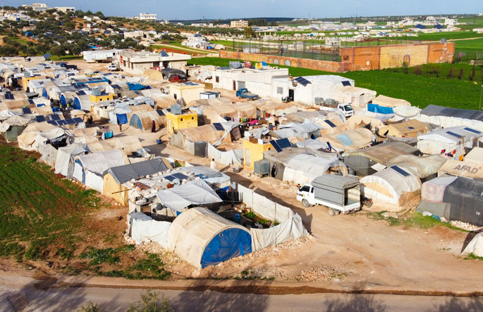 A sprawling makeshift camp with numerous tents and temporary shelters, showing one of the harsh places people wouldn’t revisit.