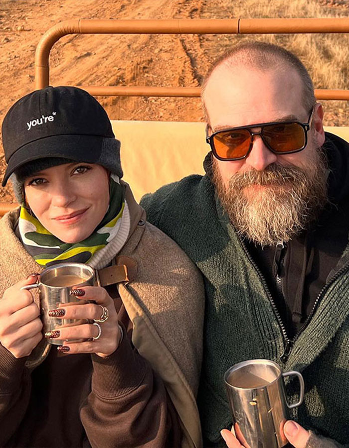 Lily Allen and David Harbour outdoors, dressed warmly, holding metal cups, capturing a candid moment together.