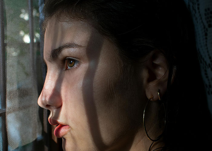 Close-up of a woman with shadows on her face, evoking a creepy atmosphere linked to unsettling things women said or did.