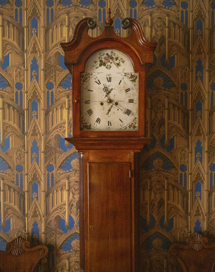 Antique wooden grandfather clock with floral details on face, set against ornate patterned wallpaper, illustrating rare coincidences.