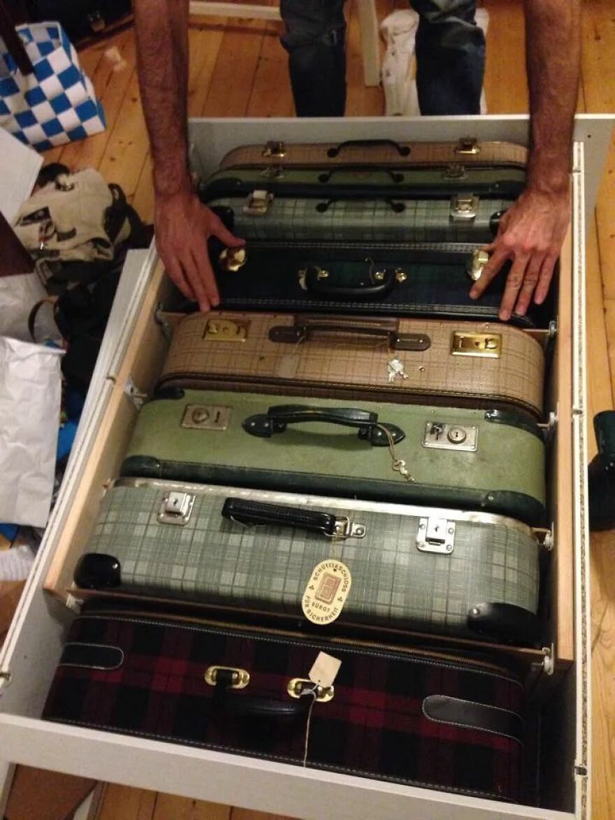 Hands organizing vintage suitcases neatly inside a drawer showcasing creative home organization hacks.