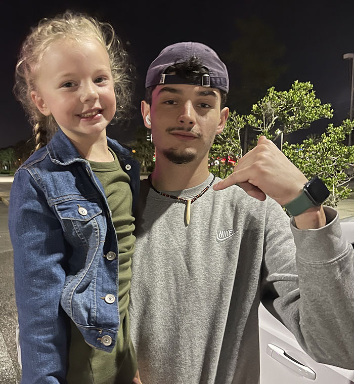 Young Florida dad-to-be wearing a cap and gray Nike sweatshirt holding a smiling young girl outdoors at night. Young Florida dad-to-be wearing a cap and gray Nike sweatshirt holding a smiling young girl outdoors at night.