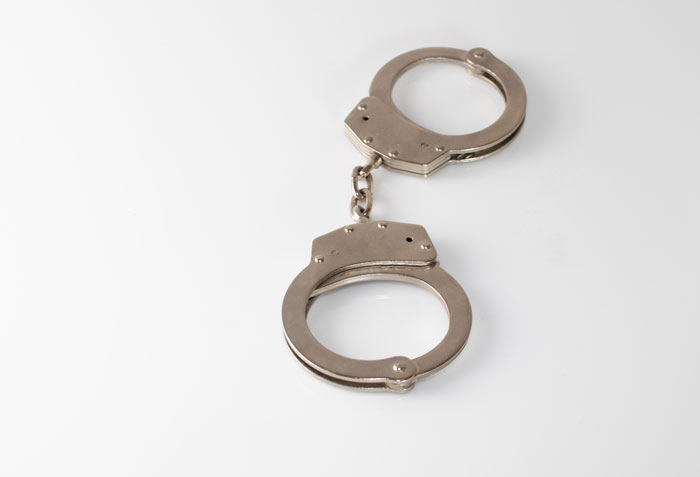 Silver handcuffs on a white surface, representing daycare workers who heard unexpected family secrets.