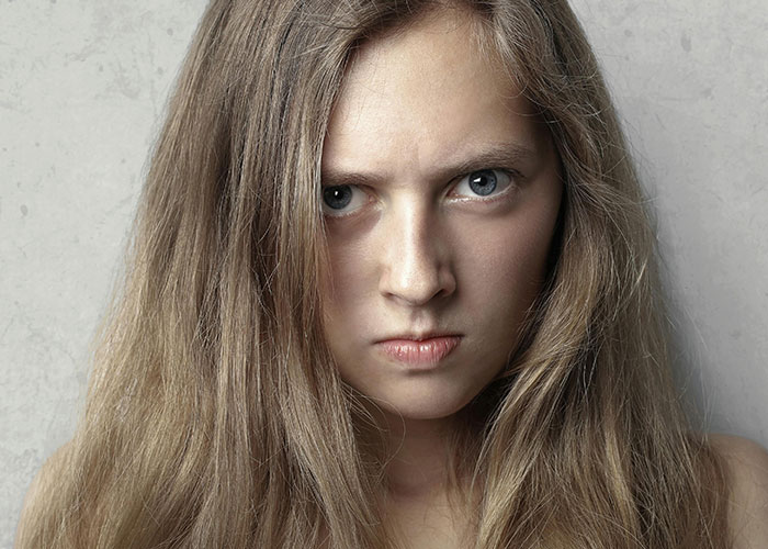 Close-up of a woman with long hair giving a creepy and intense stare, illustrating creepy things women did to men.
