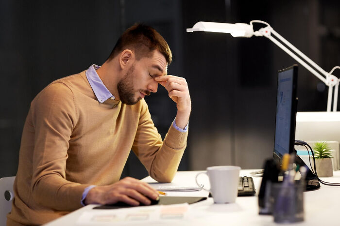 Stressed man at desk, showing signs of frustration in an unfair relationship affected by traditional gender roles.