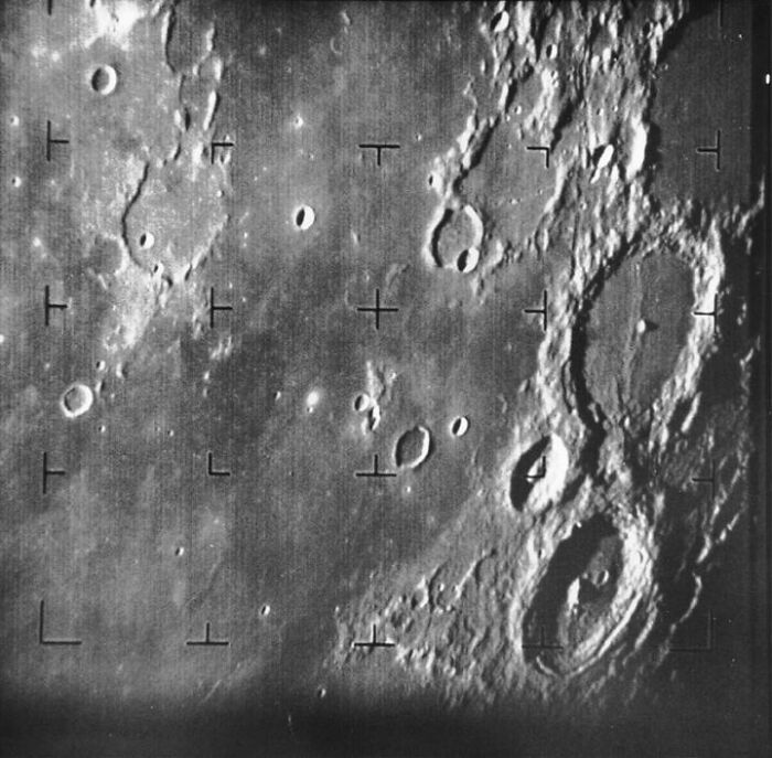 Close-up astronomy photo of the moon's surface showing detailed craters and lunar terrain features in space.