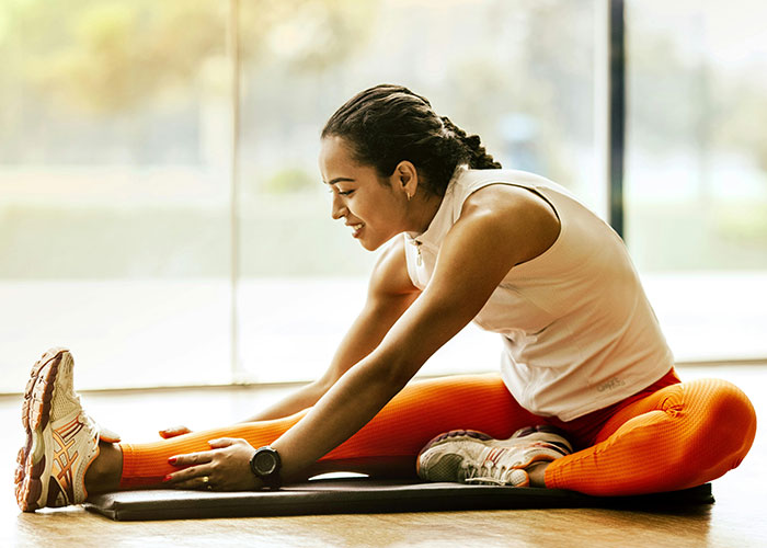 Woman in orange leggings stretching on a mat, symbolizing psychologists debunking mental health myths for wellness awareness.
