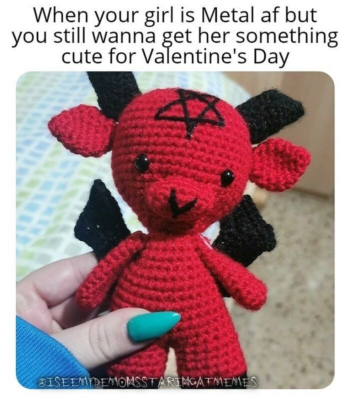 Hand holding a red crocheted demon doll with black horns and pentagram, funny relatable meme for horror and Halloween fans.