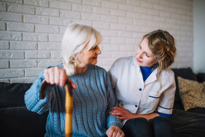 Elderly woman with dementia sharing a moment with a female caregiver in a cozy home setting.