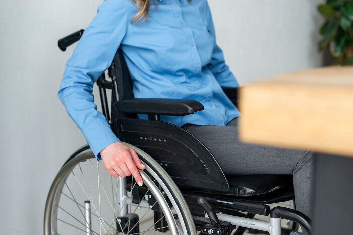 Person in a wheelchair wearing a blue shirt and gray pants, highlighting a moment of misreading social cues in daily life.