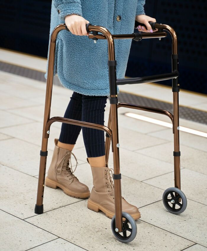 Person using a walker with beige boots and blue coat, illustrating challenges faced by people with disabilities.