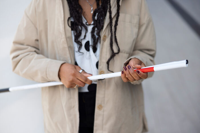 Person with disabilities holding a white cane, highlighting experiences with rude and ableist behavior endured.