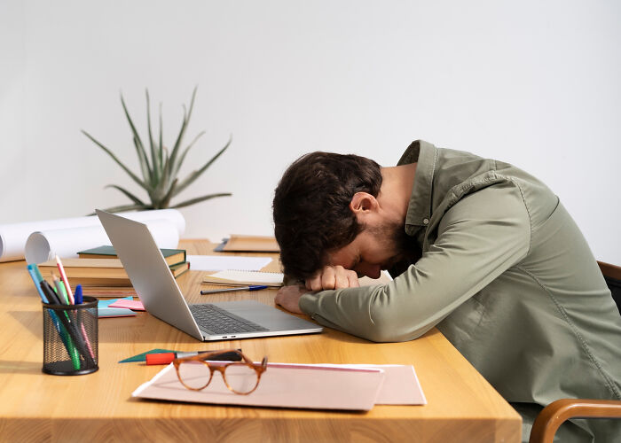 Man frustrated at desk with laptop and office supplies, illustrating the reality behind so-called genius life hacks.