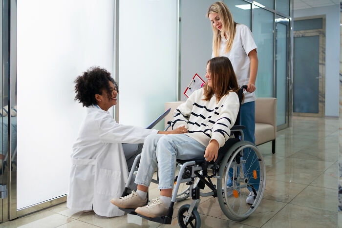 A woman in a wheelchair with healthcare workers, highlighting people with disabilities facing rude and ableist treatment.