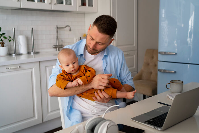 Man in a kitchen holding a baby, illustrating relationships affected by unfair gender roles and societal expectations.