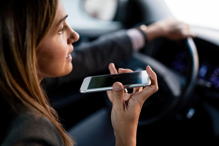 Woman speaking on smartphone while driving a car, highlighting terrifying medical conditions that show no symptoms.