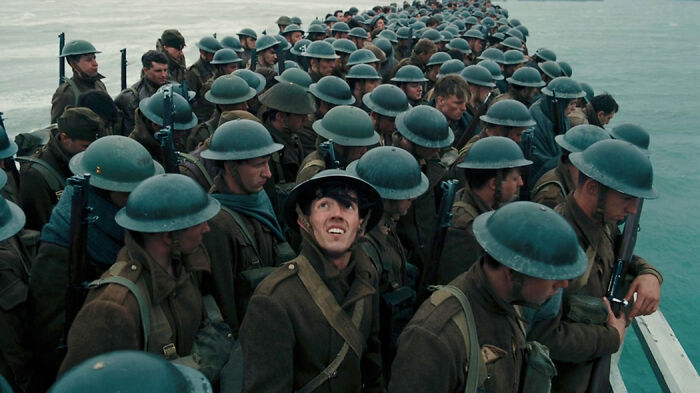 Soldiers wearing helmets and military uniforms crowded on a boat in a scene from movies based on true stories.