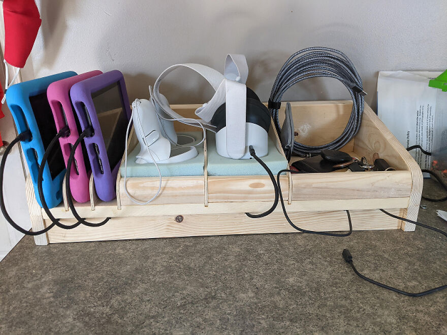 Wooden charging station organizing tablets, VR headsets, cables, and small items as a home organization hack.