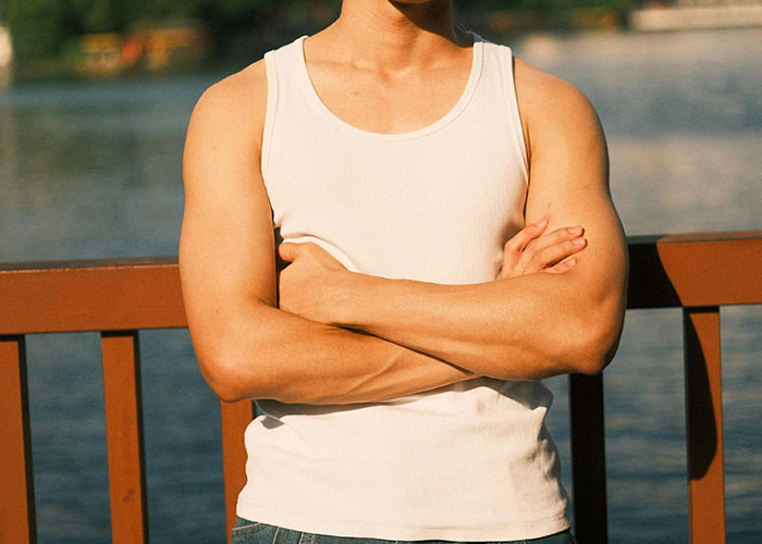 Man in white tank top with arms crossed standing by wooden railing near water, illustrating loopholes against bosses.