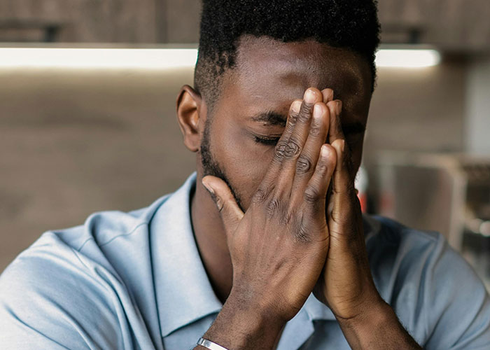 A distressed man covering his face with hands, illustrating reactions to creepy things women said or did to men.