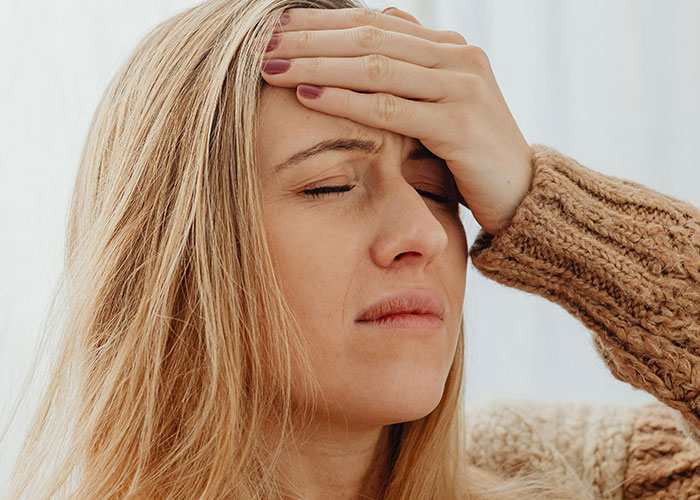 Frustrated mom holding forehead with eyes closed, feeling mortified by things her kids said or did.
