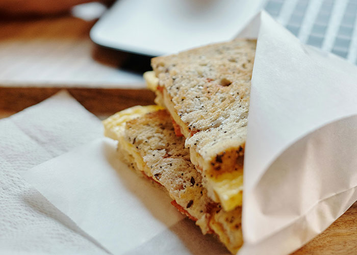 Close-up of a homemade sandwich wrapped in paper, illustrating creative loopholes against horrible bosses at work.