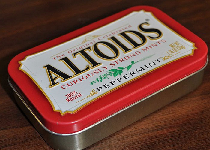 Altoids tin on wooden surface, potential container for storing bizarre cat hacks discovered by owners