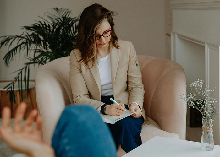 Female psychologist taking notes during a therapy session in a cozy room debunking mental health myths.