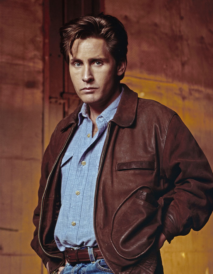 Young famous man wearing a brown leather jacket and blue shirt, representing famous men who are shorter than fans imagined.