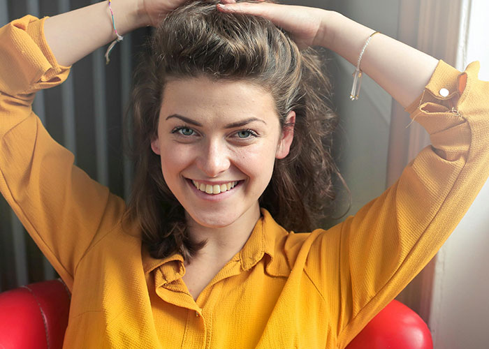 Young woman smiling and posing indoors, illustrating creepy things women said or did that left men horrified.