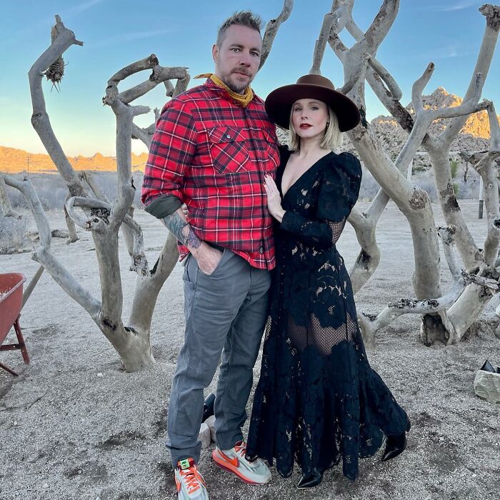 Kristen Bell and a man posing outdoors among leafless trees, highlighting Kristen Bell snubbing fans after triggering backlash.