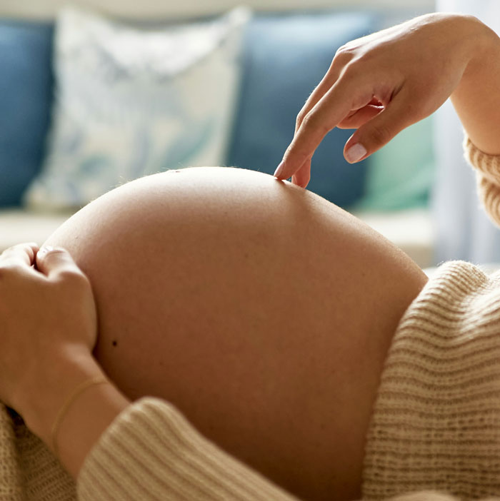 Pregnant new mom touching her belly, symbolizing the challenges of confronting MIL's unhinged behavior.