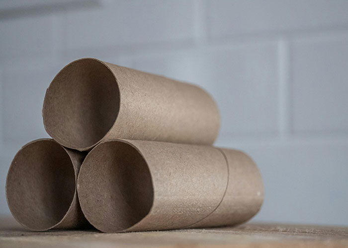 Three empty cardboard tubes stacked in a pyramid, illustrating a simple cat hack for pet owners to reuse items.