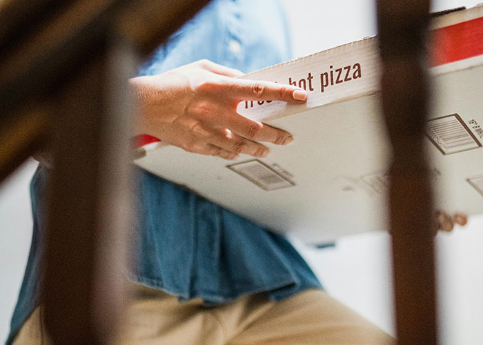 Person carrying a large pizza box indoors, illustrating creepy things women said or did to men that left them horrified.